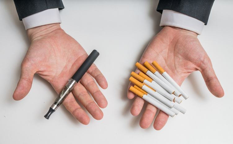 Hands holding e-cigarettes and tobacco cigarettes