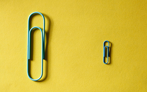Two paper clips of different sizes, one small and one large