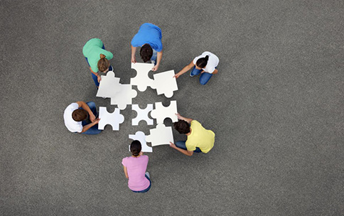 A group of young people putting a puzzle together.