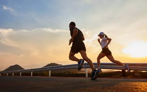 A male and a female running on the road at sunset