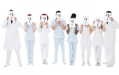 Doctors holding signs with question marks in front of their faces.