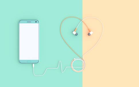 smartphone with headphones and earphones in the shape of a heart on colorful background 