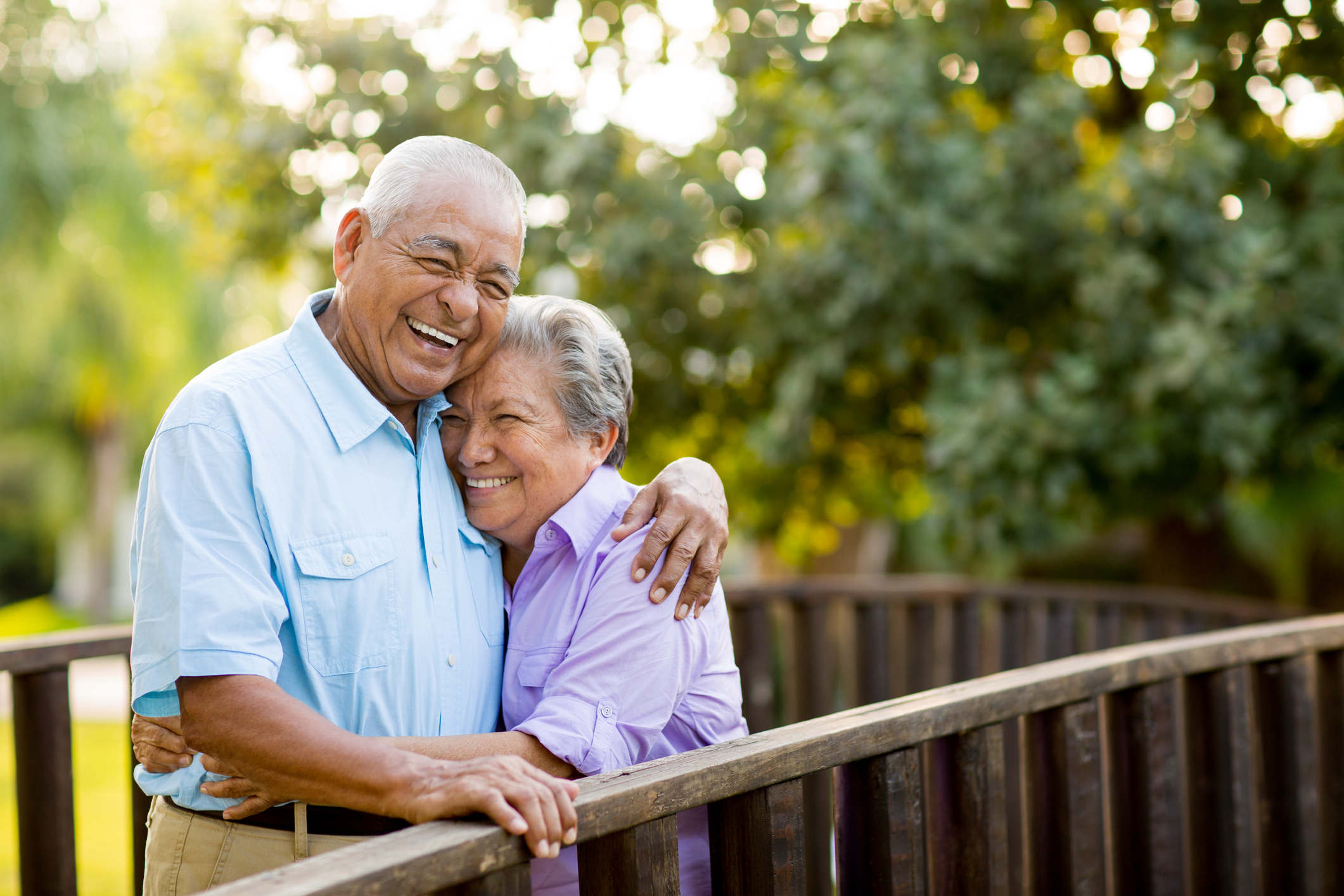 An elderly couple are shown hugging and smiling