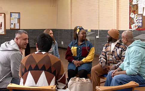 A diverse group of people is sitting in a room and having a discussion.