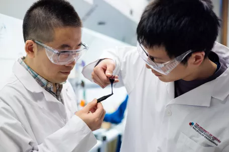 Two researchers study a piece of hydrogel semiconductor.