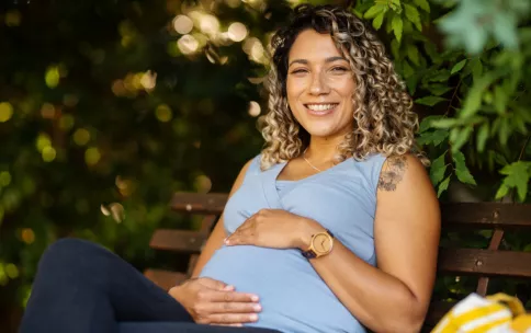 Pregnant woman sitting on a bench outdoors.